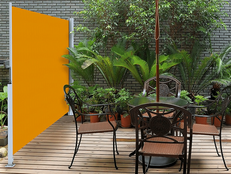 Terrasse mit Gartenmöbeln umgeben von Topfpflanzen und einer Seitenmarkise.